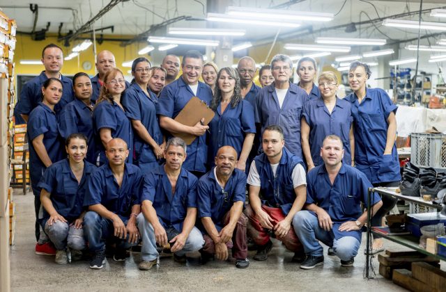 Happy group of Latin American workers at a factory looking at the camera and smiling